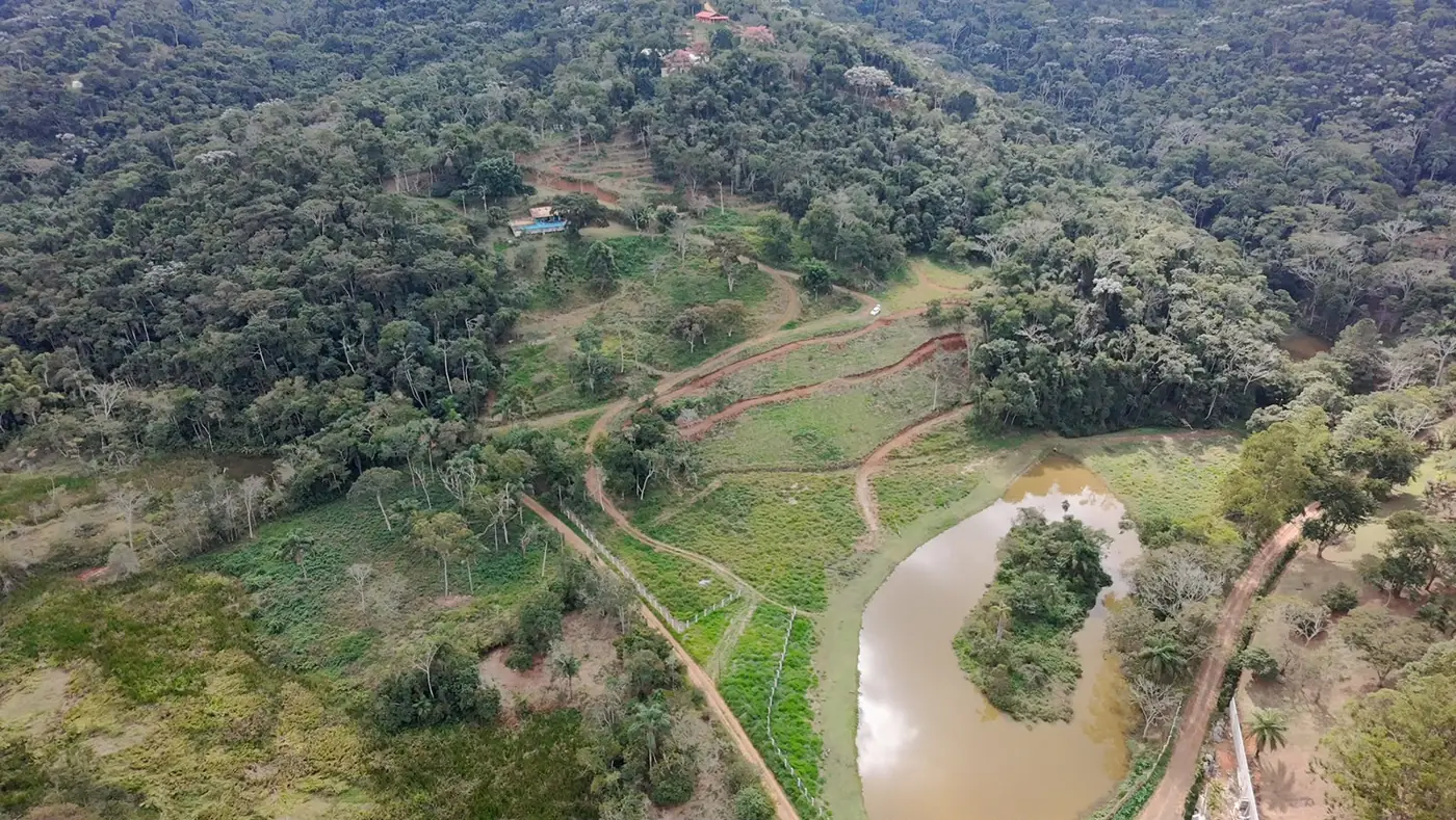 Vista aérea de trilha e represa em meio à mata preservada